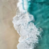 Aerial view of turquoise ocean waves crashing onto a sandy beach, creating white foam patterns along the shoreline. Beachscape art print available in A1 to A4 sizes.