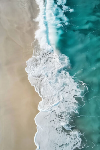 Aerial view of turquoise ocean waves crashing onto a sandy beach, creating white foam patterns along the shoreline. Beachscape art print available in A1 to A4 sizes.