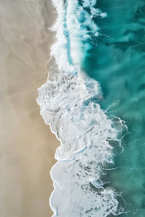 Aerial view of turquoise ocean waves crashing onto a sandy beach, creating white foam patterns along the shoreline. Beachscape art print available in A1 to A4 sizes.