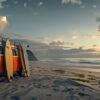 An orange van with surfboards leaning against it is parked on a sandy beach near the ocean at sunset. Surf life print available in A1 to A4 sizes.