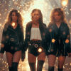 Three women in black outfits stand confidently under falling sparks and warm, glowing lights, creating a dramatic and intense atmosphere. Cinematic-style teen attitude poster available in A1 to A4 sizes.