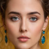Portrait of a woman with light skin, blue eyes, and wavy brown hair is wearing blue gemstone earrings and looking directly at the camera, with a blurred yellow background. Wall art print available in A1 to A4 sizes.