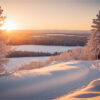 A snowy landscape with snow-covered trees and hills at sunset, with soft sunlight illuminating the scene and a frozen lake in the distance. Nature and landscape print available in A1 to A4 sizes.