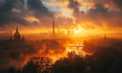 A view of Paris at sunrise with the Eiffel Tower, river, historic buildings, and city skyline illuminated by warm sunlight through dramatic clouds. Wall art print available in A1 to A4 sizes.