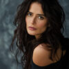 Portrait of Salma Hayek with long wavy dark hair and neutral expression, wearing an off-the-shoulder black top, posing against a mottled grey background. Wall art print available in A1 to A4 sizes.