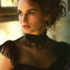 A Portrait of Natalie Portman. with wavy brown hair in an updo, wearing a sheer black dress, looks out of a window with soft light illuminating her face. Wall art print available in A1 to A4 sizes.