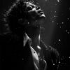 Pop icon Michael Jackson in a partially unbuttoned shirt and jacket stands under dramatic lighting with water droplets floating in the air, head tilted back and eyes closed. Striking black and white image. Wall art print available in A1 to A4 sizes.