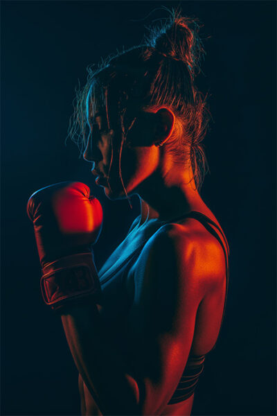 A woman in sportswear and boxing gloves stands in a boxing pose, lit by dramatic red and blue lighting against a dark background. Poster print available in A1 to A4 sizes.