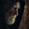 Elderly man with a white beard and mustache wearing a dark hooded cloak, shown in profile against a textured, dark background, reminiscent of Obi-Wan Kenobi from Star Wars. Fantasy art poster available in A1 to A4 sizes.