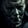 A close-up of a person wearing a pale, expressionless Michael Myers mask with visible scratches and scars, dressed in a dark outfit against a shadowy background—a chilling nod to Halloween. Horror poster available in A1 to A4 sizes.