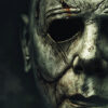 Close-up of a worn, cracked, and scarred white mask with hollow black eye holes, creating an eerie and unsettling appearance. Michael Myers from Halloween. Horror poster available in A1 to A4 sizes.
