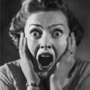Black and white photo of a woman with wide eyes and mouth open in a scream, holding her face with both hands, expressing shock or fear. Horror poster available in A1 to A4 sizes.