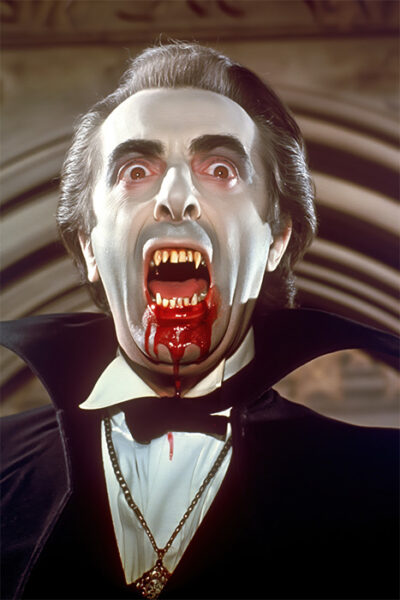 A man dressed as Dracula with pale skin, fangs, blood around his mouth, and a black cape strikes a dramatic pose—channeling vintage vampire style. Horror poster available in A1 to A4 sizes.