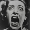 Black and white photo of a woman with wide eyes and mouth open, appearing to scream or shout, expressing intense fear or shock. Horror poster available in A1 to A4 sizes.