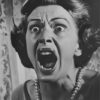 Black-and-white photo of a woman with wide eyes and mouth open, appearing to scream or shout, wearing a pearl necklace and standing indoors. Horror poster available in A1 to A4 sizes.
