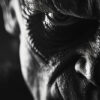 Close-up, high-contrast black and white image of a persons wrinkled face evokes a vintage feel, focusing on one intense eye and textured skin; the expression appears serious or menacing, reminiscent of Frankensteins Monster. Horror poster available in A1 to A4 sizes.