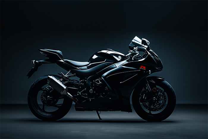 product-image-3-2 Side view of a sleek black Suzuki GSXR-1000 in a dimly lit studio setting, highlighting its aerodynamic design and modern features. Wall art print available in A1 to A4 sizes.