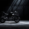 A black Kawasaki ZX10R sport motorcycle is parked on a dimly lit concrete floor with beams of light shining down from above. Wall art print available in A1 to A4 sizes.