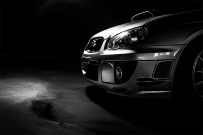 Close-up view of the front right side of a silver Subaru Impreza with prominent headlights, in a dimly lit setting. Wall art print available in A1 to A4 sizes.