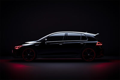 A black Volkswagen Golf hatchback viewed in profile against a dark background, with red accent lighting highlighting its outline and wheels. Wall art print available in A1 to A4 sizes.