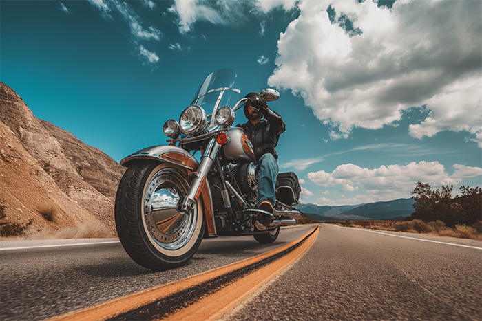 product-image-3-2 A motorcyclist rides a large cruiser bike on a two-lane road through a scenic, mountainous landscape under a partly cloudy sky. Wall art print available in A1 to A4 sizes.