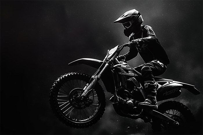 product-image-3-2 A motocross rider in full gear and helmet jumps a dirt bike against a dark, dramatic background with strong lighting and contrast. Wall art print available in A1 to A4 sizes.