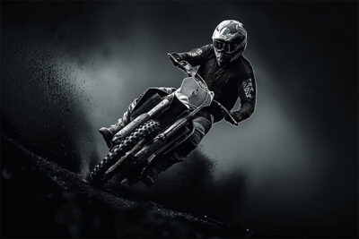 A person wearing a helmet and protective gear rides a motocross bike at speed, kicking up dirt against a dark, dramatic background. Wall art print available in A1 to A4 sizes.