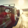 A vintage hot rod car speeds down a sunlit racetrack, with smoke trailing from its tires and blurred motion in the background. Wall art print available in A1 to A4 sizes.