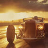 A vintage hot rod car with headlights on drives on a wet road at sunset, with clouds and a fence visible in the background. Wall art print available in A1 to A4 sizes.