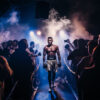 A male boxer in white trunks walks down a lit runway toward the ring, surrounded by a cheering crowd and smoke effects. Poster print available in A1 to A4 sizes.