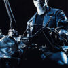 A man in sunglasses and a leather jacket sits on a motorcycle holding a shotgun. The text reads Terminator 2: Judgment Day, the iconic 1991 film. Movie poster print available in A1 to A4 sizes.