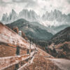 A wooden fence lines a grassy hill with a winding mountain path, forested slopes, and jagged mountains in the background under a cloudy sky. Nature and landscape poster print available in A1 to A4 sizes.