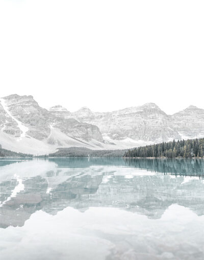 A still Mountain Lake reflects pine trees and snow-capped mountains under a bright, overcast sky. Nature and landscape poster print available in A1 to A4 sizes.