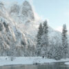 Snow-covered trees and mountains, including a snowy rockface, stand beside a calm river under a pale sky in a winter landscape. Nature and landscape poster print available in A1 to A4 sizes.