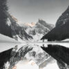 Snow-covered mountains and trees are reflected in the calm, mirror-like surface of Mountain Lake under a clear sky. Nature and landscape poster print available in A1 to A4 sizes.