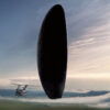 A large, dark, oval-shaped alien spacecraft hovers above a grassy field with a military helicopter nearby beneath a cloudy sky. The word ARRIVAL is at the bottom, referencing the 2016 movie Arrival. Movie poster print available in A1 to A4 sizes.
