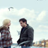 A woman and a man stand on a rocky shoreline with seagulls flying around, both looking serious. The title Manchester by the Sea (2016) appears at the top of the image. Movie poster print available in A1 to A4 sizes.