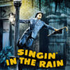 A man in a suit and hat hangs onto a lamppost, holding an umbrella, singing joyfully in heavy rain with the words Singin in the Rain, the classic musical 1952 movie, in bold yellow letters below. Movie poster print available in A1 to A4 sizes.