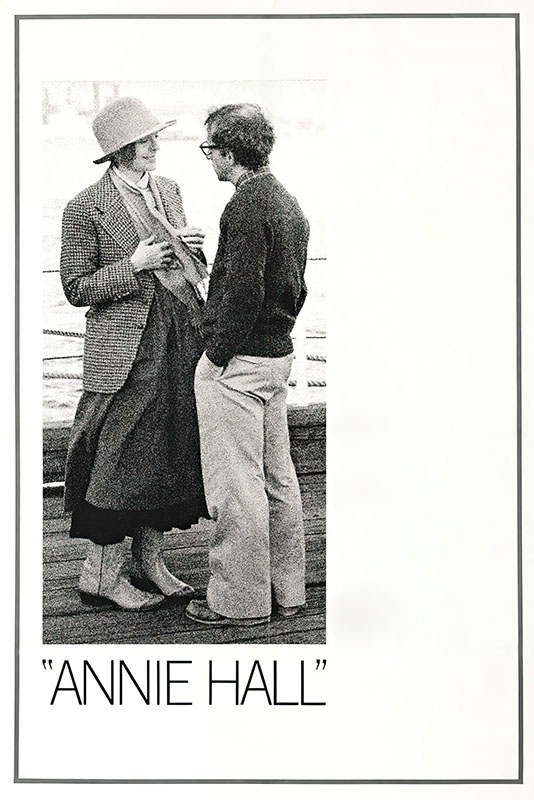 Product-Images_0003_Annie Hall.jpg Two people stand facing each other, talking on a wooden walkway; one wears a hat and long skirt, the other glasses and casual clothes—a scene from Annie Hall (1977). The text below reads ANNIE HALL. Movie poster print available in A1 to A4 sizes.